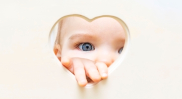 Baby looking through heart shape