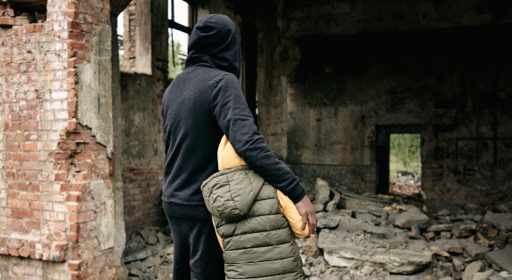 Adult and child look over the ruins of a building.